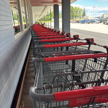 Save A Lot - Multiple shopping carts are arranged in a line outside a retail store, under a covered walkway with large windows and parking lot in the background. - Grocery Near Me - Chaffee, New York