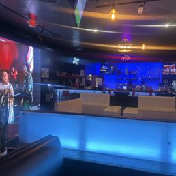 Large screen tv along with other tv's surrounding the restaurant and an open bar.
