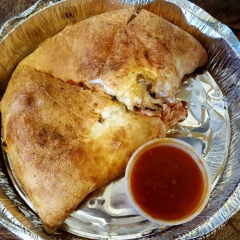 Calzone - a plate of food with a side of sauce - Pizza Near Me - Kirkland, Quebec Calzone - a plate of food with a side of sauce - Pizza Near Me - Kirkland, Quebec