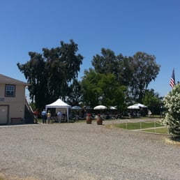 a gravel parking lot with tables and umbrellas