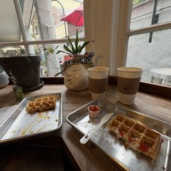 Wild Culture - Two lattes and waffles-one stuffed with apricot jam and another with sesame seeds and creamy feta, fermented red chili sauce on the side.
