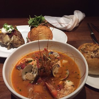 Nick's Manhattan Beach - Cioppino comes with a mini sourdough loaf. Loaded baked potato in the background. - American Near Me - Manhattan Beach, California Nick's Manhattan Beach - Cioppino comes with a mini sourdough loaf. Loaded baked potato in the background. - American Near Me - Manhattan Beach, California