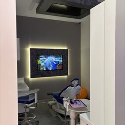 Clean dental room with TVs on the wall & ceiling