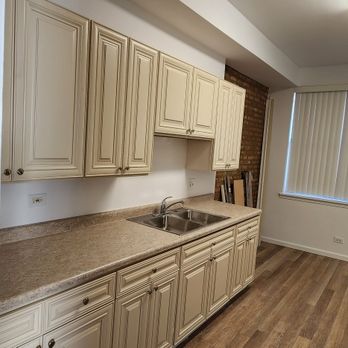 PS Home Improvement - a kitchen with white cabinets and wood floors - Tiling Near Me PS Home Improvement - a kitchen with white cabinets and wood floors - Tiling Near Me