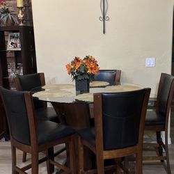 Eclectica Home - #1 Pic - Barista glass table top wood base, 5 black leather looking chairs. (Good condition B+ grade)