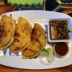 Los Arcos - Birria Tacos: Three Grilled Corn Tortillas Filled with Cheese. Birria Beef. Cilantro, Onion and Red Sauce. Served with a Savory Consommé.
