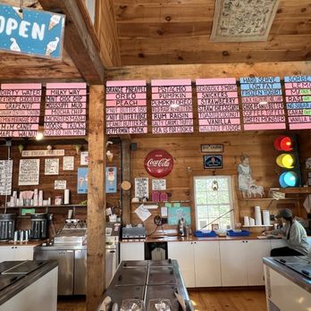 Scoop Deck - Inside Menu - Inside an ice cream shop, with menu boards displaying flavors and prices, a staff member working at the counter, and a traffic light decoration on the wall. - Ice Cream & Frozen Yogurt Near Me - Wells, Maine