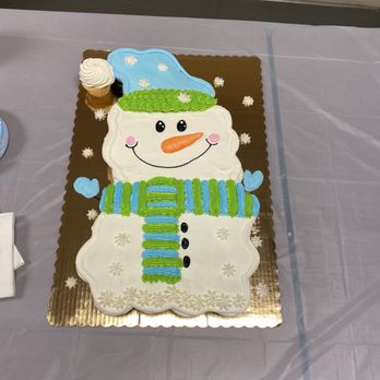 Roberto's Bakery - Cupcake cake - A cake shaped like a snowman with icing details, including a carrot nose, eyes, and a scarf, placed on a table. - Bakeries Near Me - Taylor, Michigan