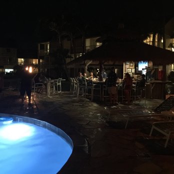 The Sandbar - a pool at night with people sitting at tables - Lounges Near Me - Kapaa, Hawaii