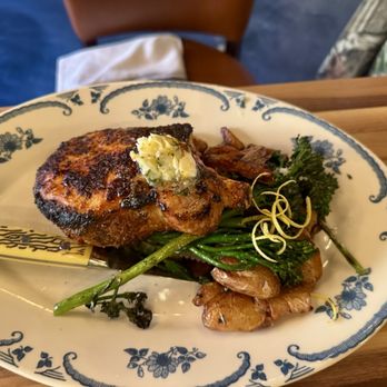 Fire + Wine - Park Ridge - A dish featuring a grilled piece of meat topped with butter, served with green vegetables and herbs on a floral-patterned plate. - Italian Near Me - Park Ridge, Illinois