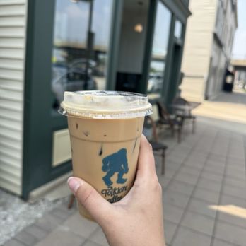 Folklore Coffee - A person holds a plastic cup of iced coffee with a Folklore Coffee logo outside a coffee shop in Lemont, Illinois. - Coffee & Tea Near Me - Lemont, Illinois
