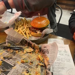 An empty plate of nachos and a bacon cheeseburger with fries