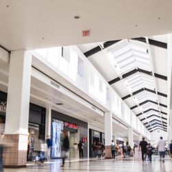 Stonewood Center - Shoppers pass Hollister and other stores in a sunlit Stonewood Center corridor.