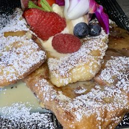 a plate of french toast with fruit and powdered sugar a plate of french toast with fruit and powdered sugar