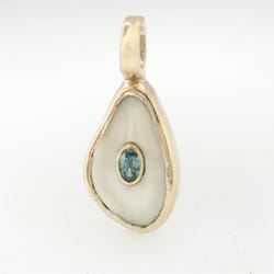 Daniel J. Reynolds Jeweler - Elk tooth Ivory pendant with inset blue zircon in 14ky.