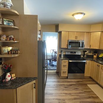 Build Right 518 - A kitchen featuring light wooden cabinets, black granite countertops, and stainless steel appliances including a microwave and oven. - General Contractors Near Me