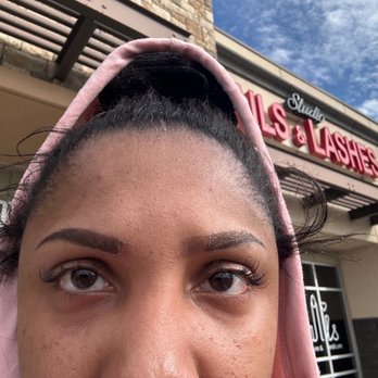 STUDIO NAILS & LASHES - A woman with well-groomed eyebrows and long eyelashes is photographed outdoors in front of a beauty salon named 'Studio Nails & Lashes.' - Nail Salons Near Me - El Paso, Texas