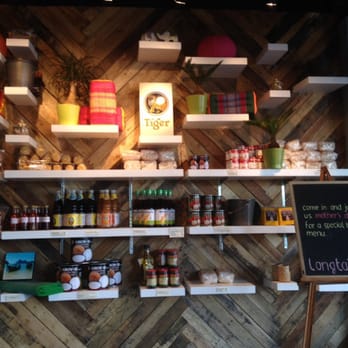 Longtail Kitchen - Wall of goods for sale including giant size tins of coconut milk. - Thai Near Me - New Westminster, British Columbia