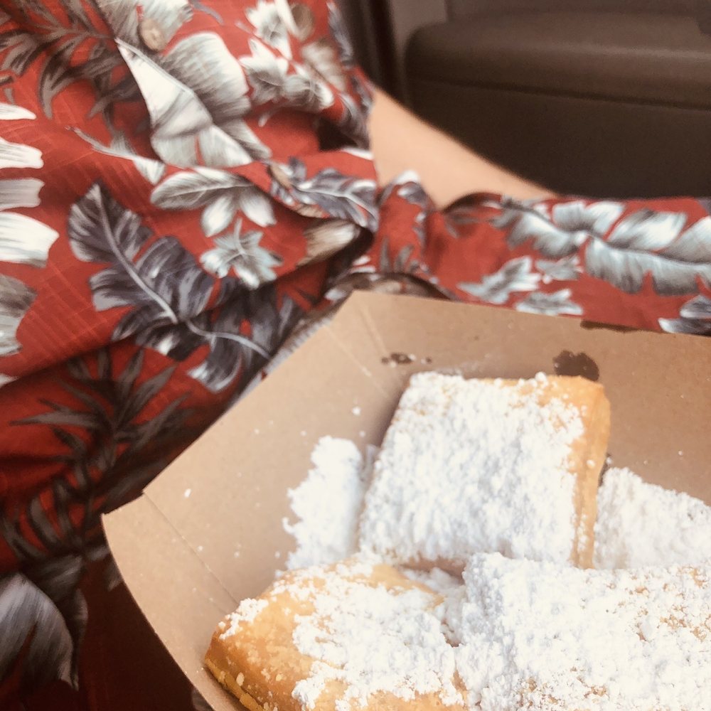 a woman holding a box of beignets a woman holding a box of beignets