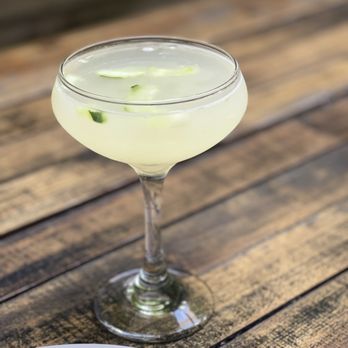 Oregano - a cocktail in a coupe glass on a wooden table - Italian Near Me - Brooklyn, New York Oregano - a cocktail in a coupe glass on a wooden table - Italian Near Me - Brooklyn, New York