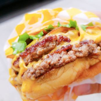 Rudy - a hand holding a sandwich with meat, cheese, and lettuce - Burgers Near Me - Toronto, Ontario