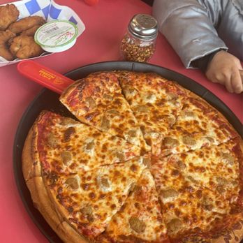 Rocky's Pizzeria - a man sitting at a table with a pizza in front of him - Pizza Near Me - North Chicago, Illinois