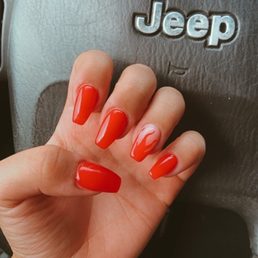Red acrylic gel nails with a red flame on the ring finger.