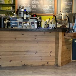 a coffee shop counter with a menu on the wall a coffee shop counter with a menu on the wall