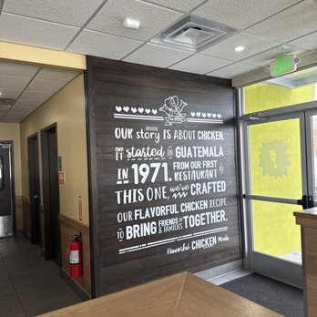 Pollo Campero - A dark wooden wall features a white painted story about chicken, mentioning Guatemala and the year 1971, inside Pollo Campero in Nottingham, MD. - Chicken Shop Near Me - Nottingham, Maryland
