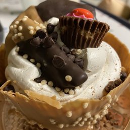 a chocolate cupcake topped with whipped cream and candy a chocolate cupcake topped with whipped cream and candy