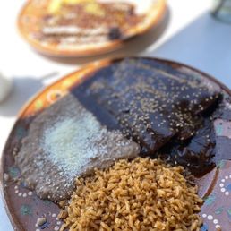 Mole - A plate with mole enchiladas, Mexican rice, and refried beans, served on a decorative ceramic dish.