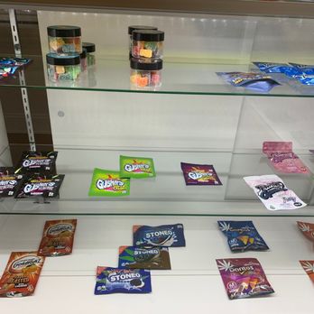 Mr Nice Guys - A glass display case with several snack packages and candies inside, some scattered and some stacked, in a retail setting. - Cannabis Dispensaries Near Me - Baltimore, Maryland