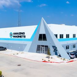 Amazing Magnets - Amazing Magnets headquarters building with bold logo, modern triangular entrance, and a full parking lot, surrounded by trees.