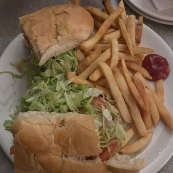 Armstrong's - Mushrooms Steak Hoagie - A plate contains a partially eaten sandwich with shredded lettuce and tomato, French fries, and a dollop of ketchup, set on a table. - American Near Me - Pittsburgh, Pennsylvania