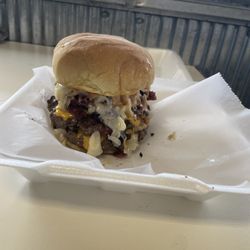 Over The Top Sandwich - Smash-A-Rue A delectable fusion of cheeseburgers and Rueben sandwiches stacked tall in a tower of deliciousness. Brace yourself for Amazing
