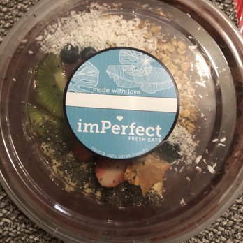 imPerfect Fresh Eats - Açai bowl - A transparent plastic container holds an acai bowl topped with sliced kiwi, strawberries, blueberries, coconut flakes, and granola, with a label from imPerfect Fresh Eats. - Acai Bowls Near Me - Toronto, Ontario