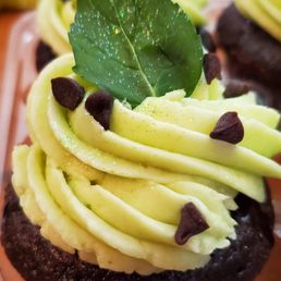 Chocolate cupcakes with green mint buttercream, mini chocolate chips, and a mint leaf on top