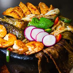 Quetzal Authentic Mexican Cuisine - "Molcajete Oaxaqueño" -- a sizzling mix of grilled meats, shrimp, cactus, and cheese, served in a hot stone bowl. A true Oaxacan feast!