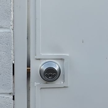 Keyway Locksmith - Installed a double dead bolt lock for security door in our back yard. - The image shows a metallic lock installed on a white door, with part of a brick wall visible on the left. - Keys & Locksmiths Near Me - Walnut, California