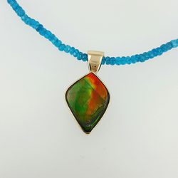 Legend Jewelers by Mark Priest - One of our custom designs. Ammolite set in a yellow gold bezel put on a necklace of blue apatite beads.