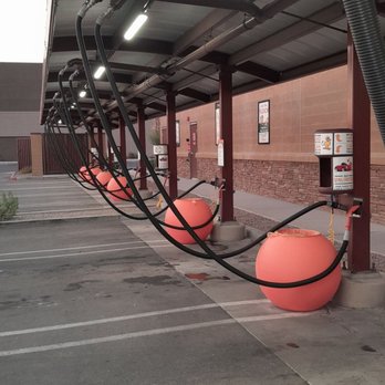 Quick Quack Car Wash - It works great for us short folks who can't reach up too high - Multiple vacuum stations with orange spherical units are positioned along a covered area at a car wash facility, with parking spaces nearby. - Car Wash Near Me - Gilbert, Arizona