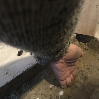 Girls 'n' Tools - Water is deep enough to cover my fingers - A hand is reaching into a gap between a wall and floor during construction or renovation work, with visible dirt and building materials. - General Contractors Near Me - Danielson, Connecticut