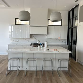 Ricardo Parra Construction Group - Modern luxury kitchen with glossy white cabinetry, oversized stone island, full-height backsplash, and sleek contemporary lighting. - Cabinetry Near Me - Delray Beach, Florida Ricardo Parra Construction Group - Modern luxury kitchen with glossy white cabinetry, oversized stone island, full-height backsplash, and sleek contemporary lighting. - Cabinetry Near Me - Delray Beach, Florida