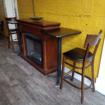 Bank Square Coffeehouse - A table over a fireplace and two chairs. - Coffee & Tea Near Me - Beacon, New York