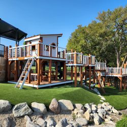 Backyard Fun Factory - Modern Design playset with bridges and multi-level platforms on uneven terrain.