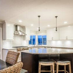 Maven Home Interiors - White Shaker Like Cabinetry on perimeter with a black stain on island. This kitchen remodel features quartz countertops.