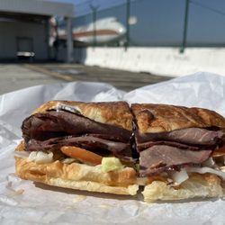 Dough Boy Donuts - Roast beef on croissant with a 747 in the background
