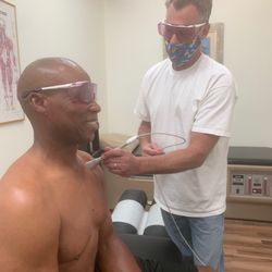 Cool Breeze Chiropractic - Dr. Phillip Lewis treating Byron Scott,NBA Head Coach and 3 time Champion, with laser shoulder therapy at Cool Breeze Chiropractic Center