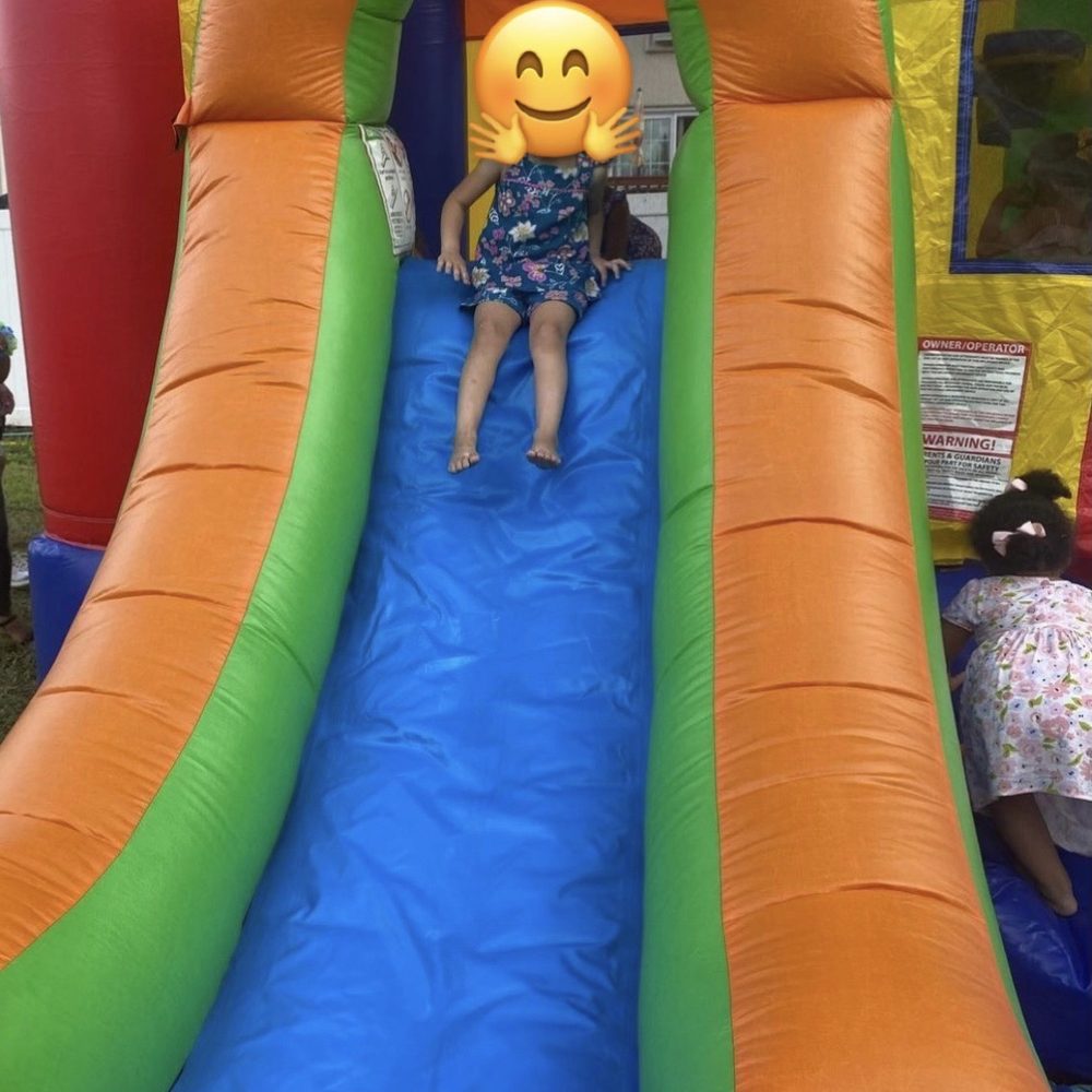 Bouncy World - Child sliding on the slide of a bouncy house - Bounce House Rentals Near Me