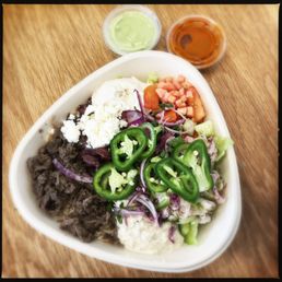 Naya bowl with beef shawarma and a ton of fixin's, red & green hot sauces on the side